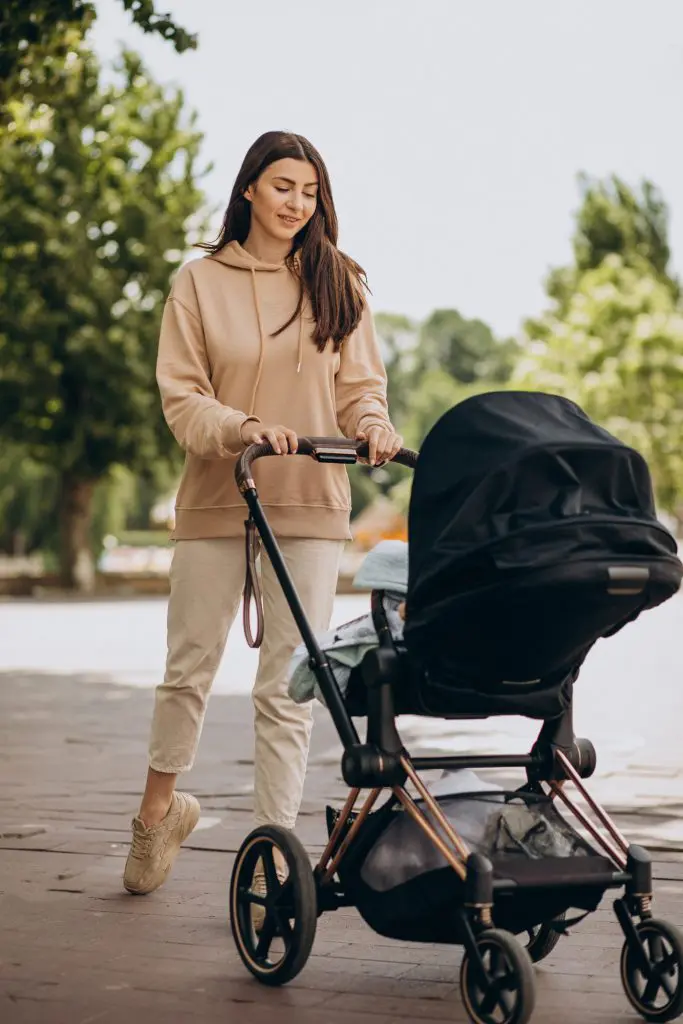 Young mother walking with baby carriage in park mother-walking-with-baby stroller park